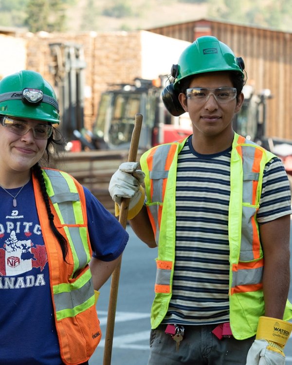 a man and a woman wearing hard hats and safety vests are standing next to each other .