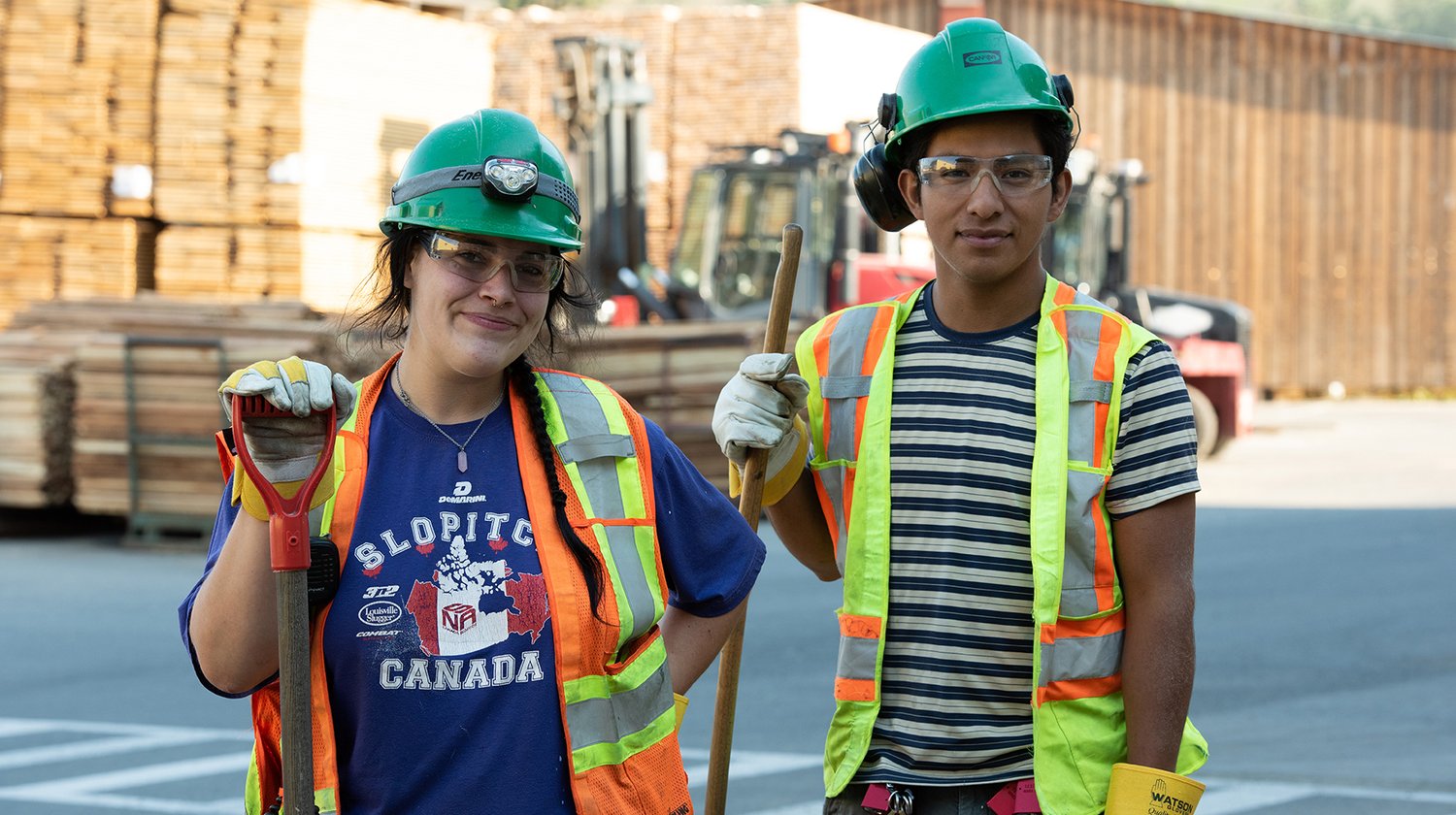 a man and a woman wearing hard hats and safety vests are standing next to each other .