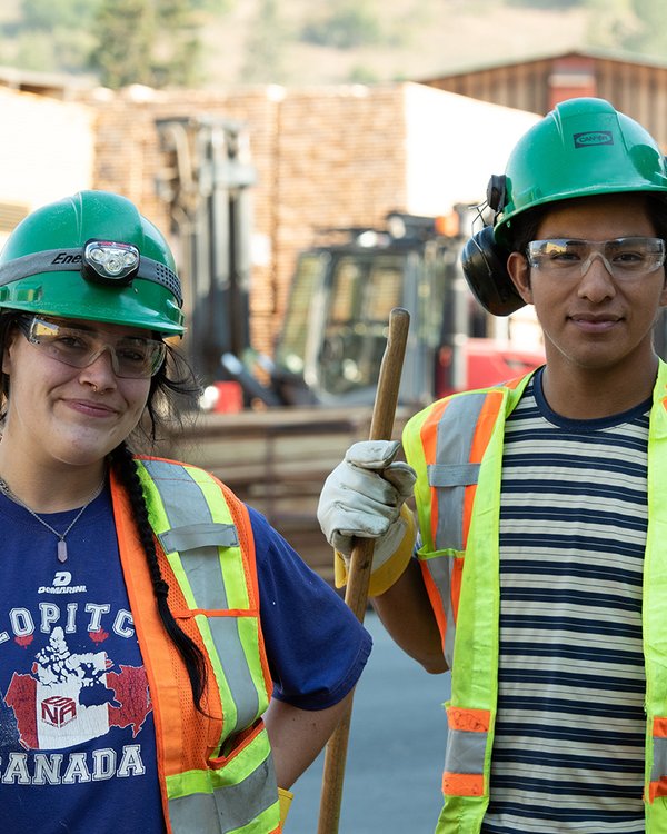a man and a woman wearing hard hats and safety vests are standing next to each other .