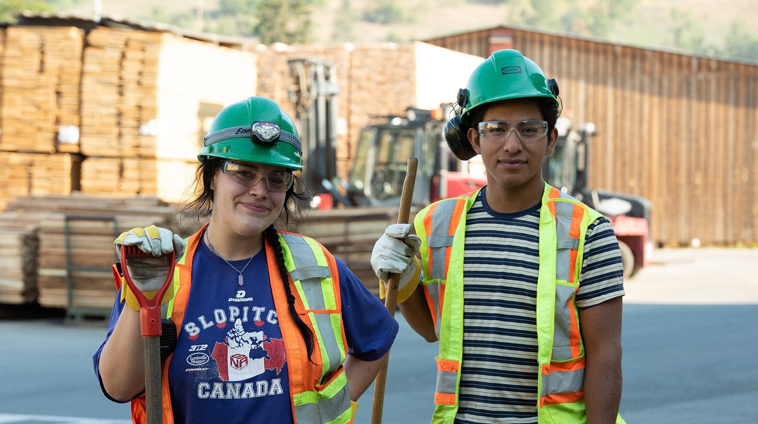 a man and a woman wearing hard hats and safety vests are standing next to each other .