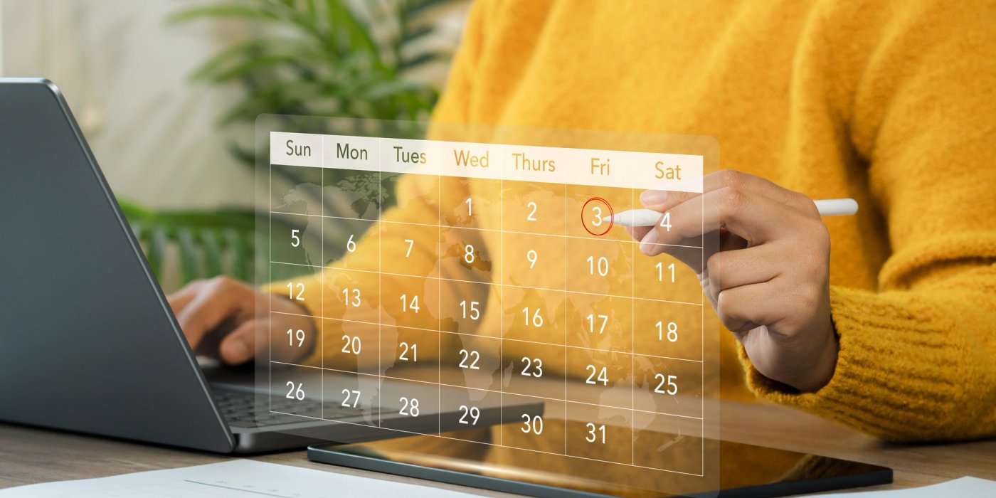 a person is looking at a calendar on a tablet while using a laptop .