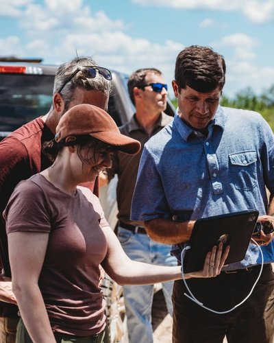 a group of people are standing in front of a truck looking at a tablet .