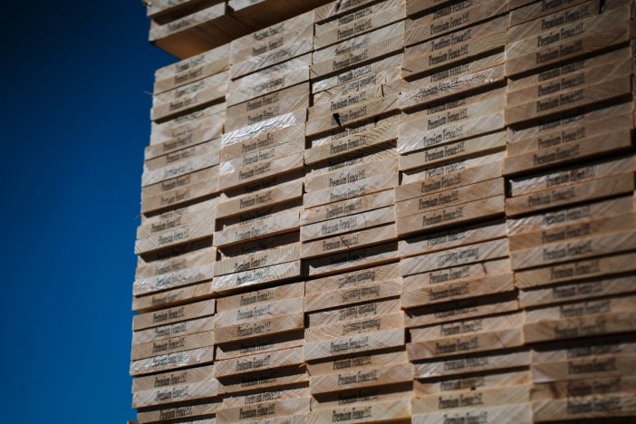 a large stack of fence boards against a blue sky .
