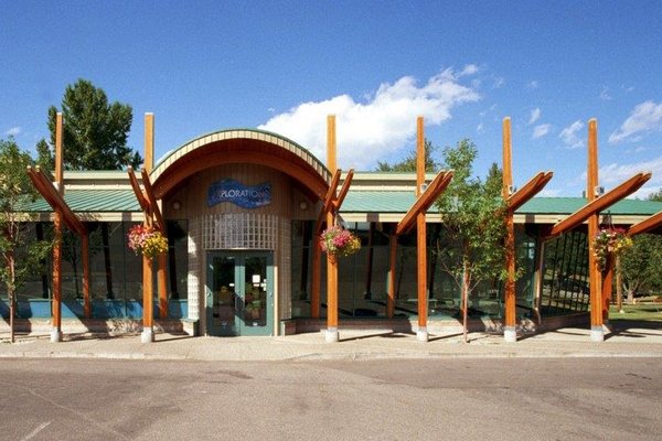 the front of a building with a green roof and wooden beams.