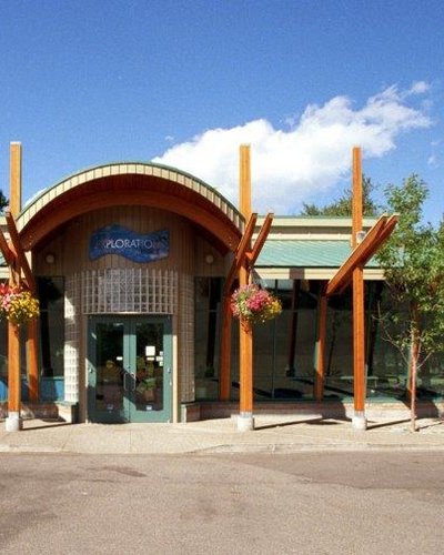 the front of a building with a green roof and wooden beams.