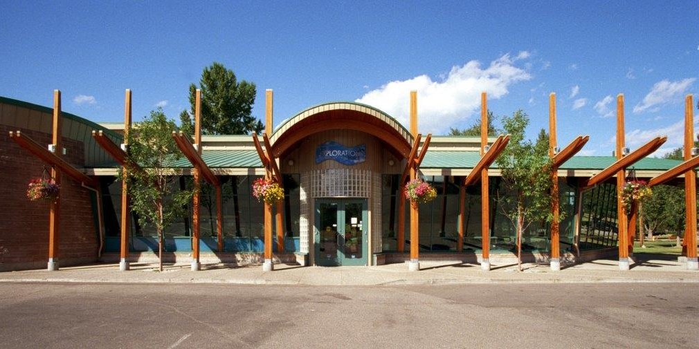 the front of a building with a green roof and wooden beams.