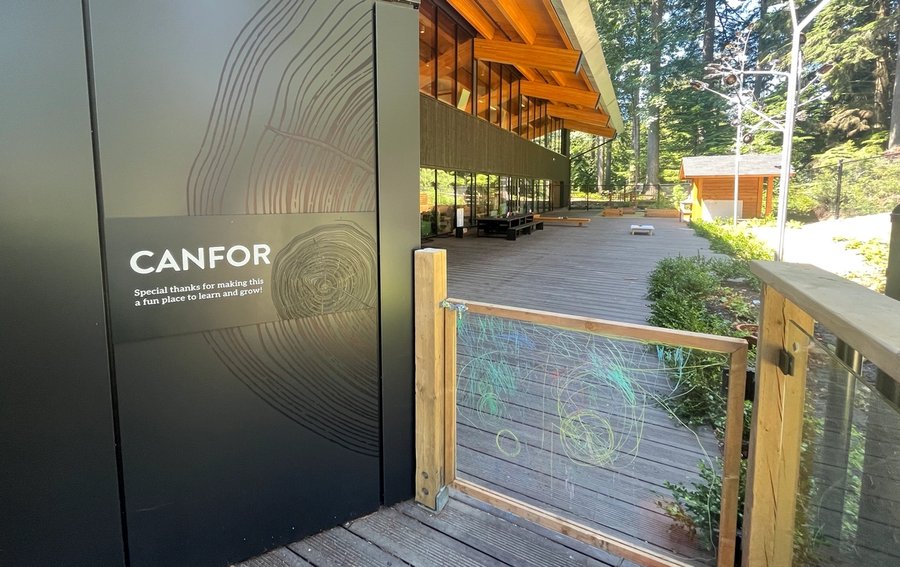 a wooden walkway leading to a building with a sign that says canfor .
