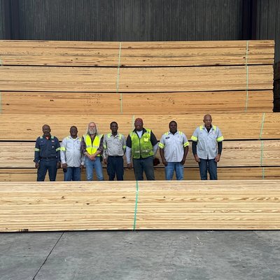 a group of men are standing in front of a large stack of wood .