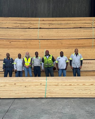 a group of men are standing in front of a large stack of wood .