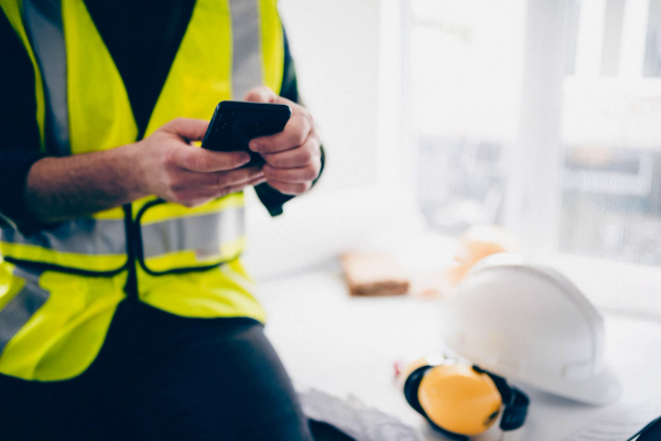 a man in a yellow vest is using a cell phone