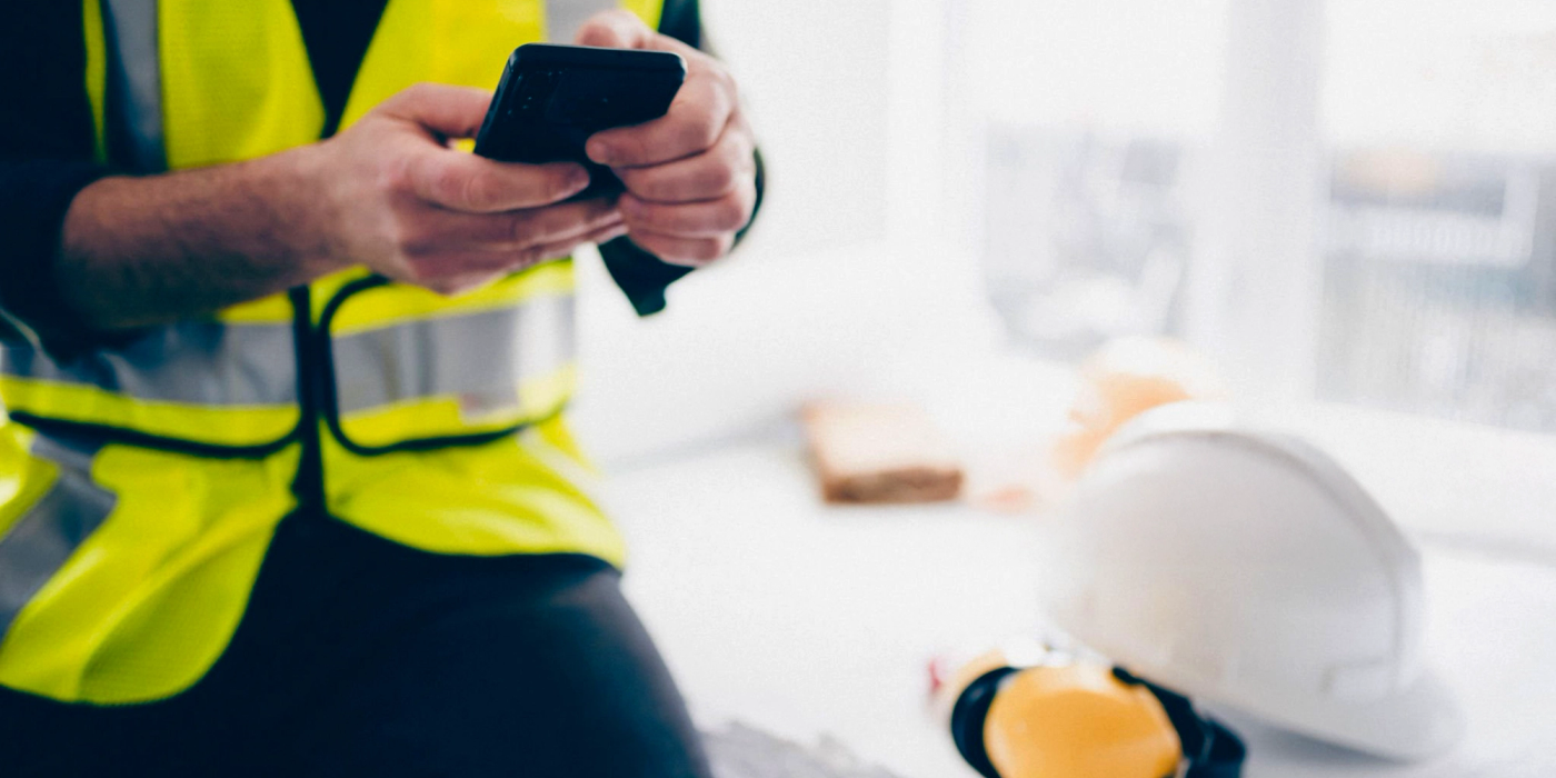 a man in a yellow vest is using a cell phone