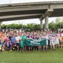 a large group of people are posing for a picture under a bridge .