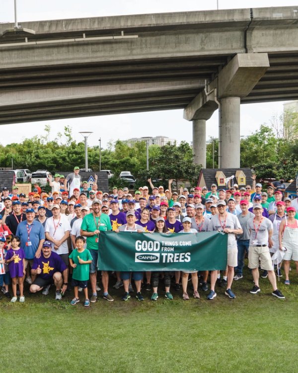 a large group of people are posing for a picture under a bridge .
