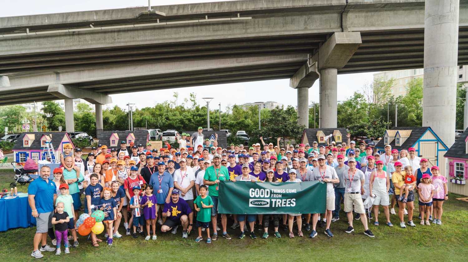 a large group of people are posing for a picture under a bridge .