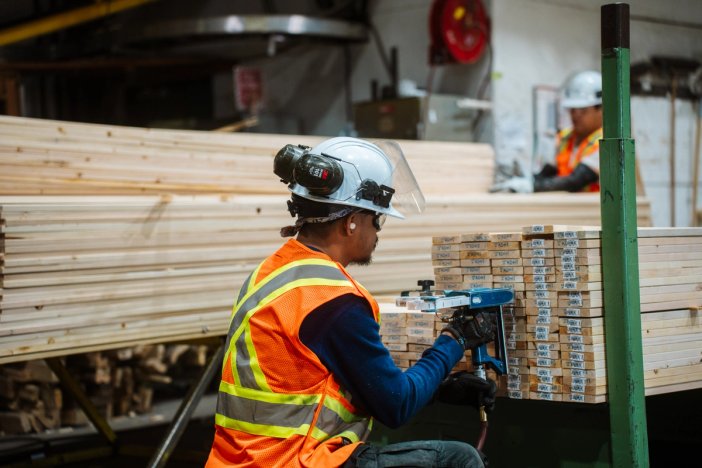 a man wearing a hard hat and safety vest is working in a factory .