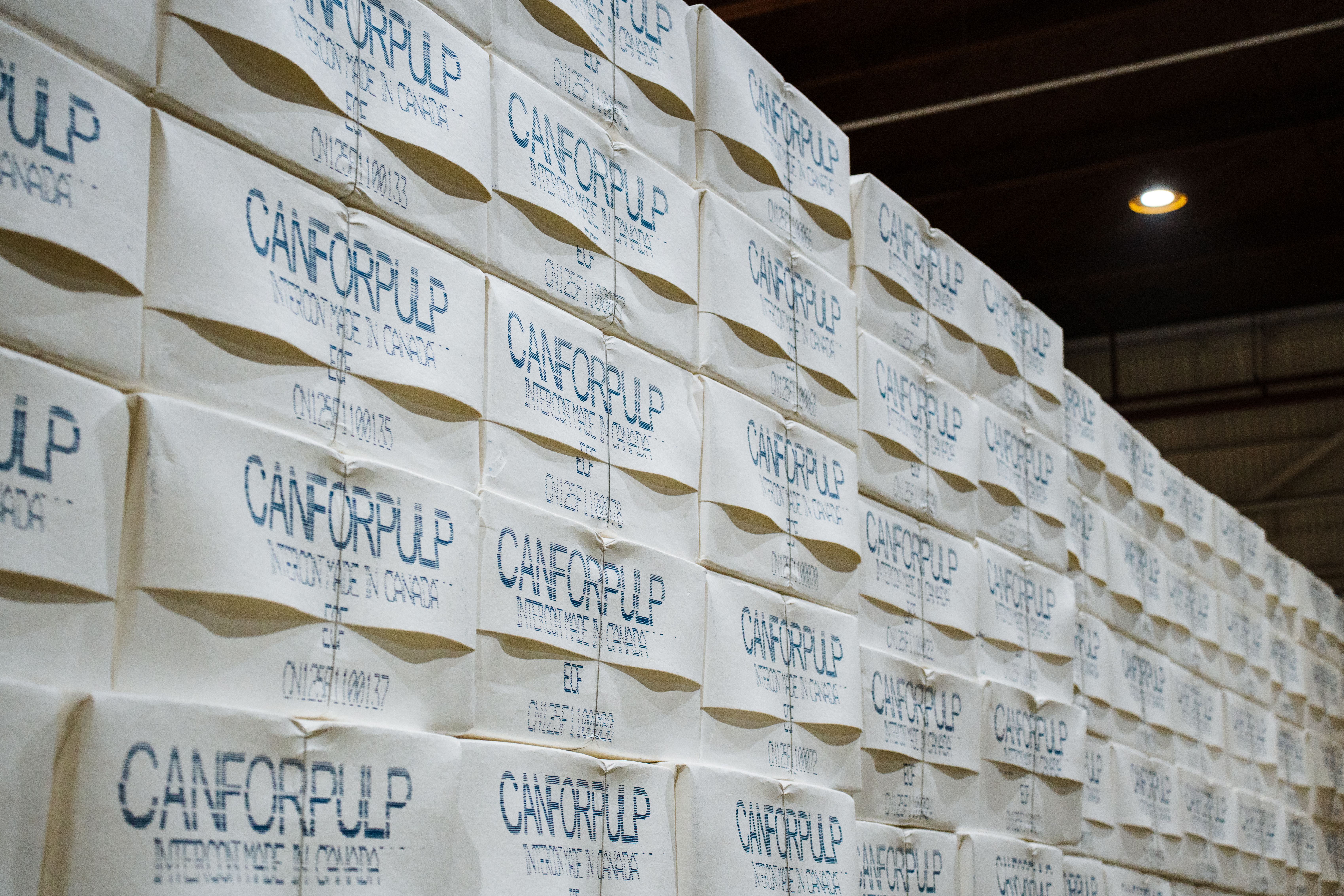 a warehouse filled with lots of bundles of finished pulp sheets stacked on top of each other .