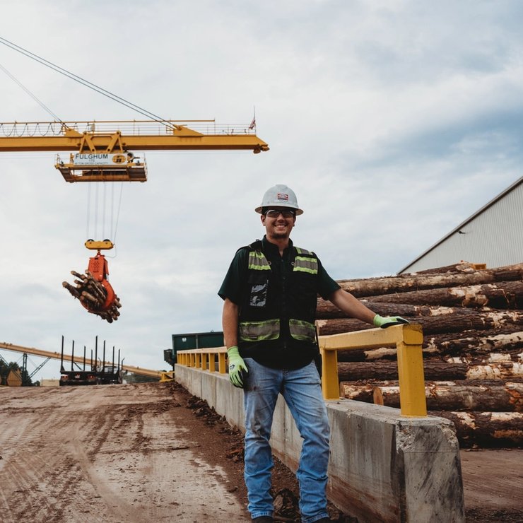 a man in a hard hat is standing in front of a crane .