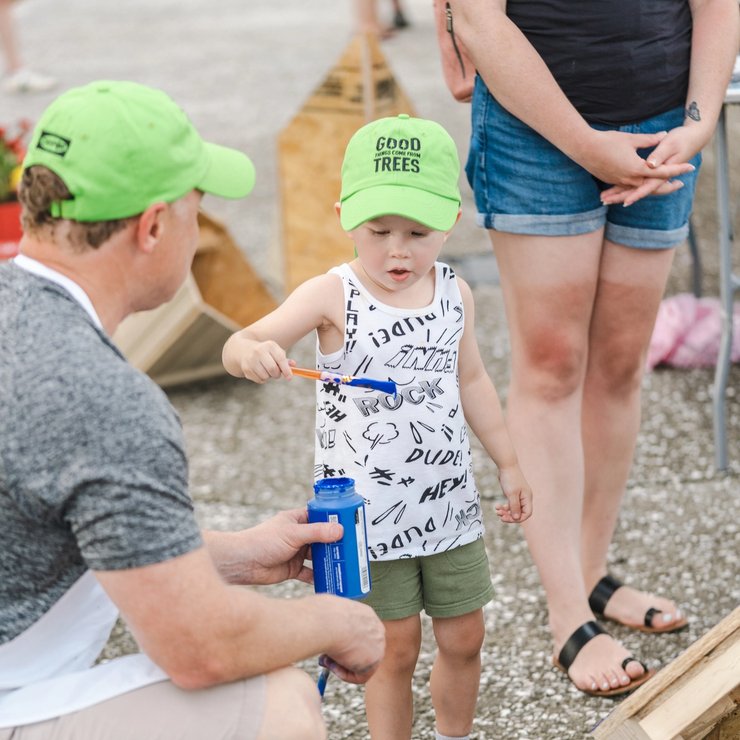 a little boy wearing a green hat that says good trees