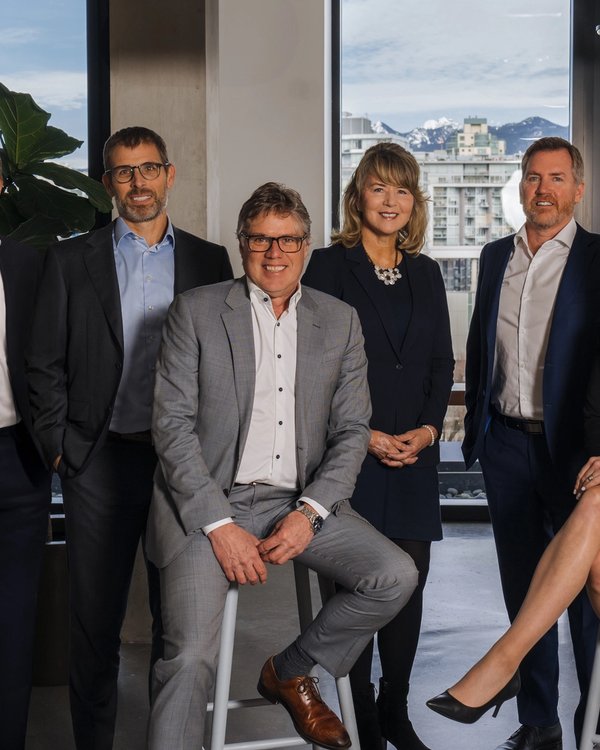 Six professionals in business attire in a modern office with city and mountain views.