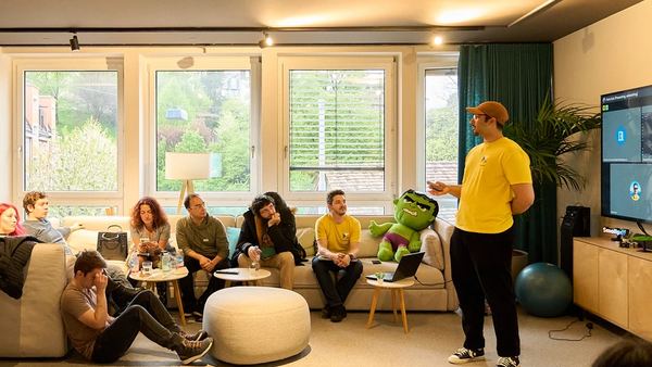 Attendees listening to a speaker in a lounge at a ZurichJS meetup.