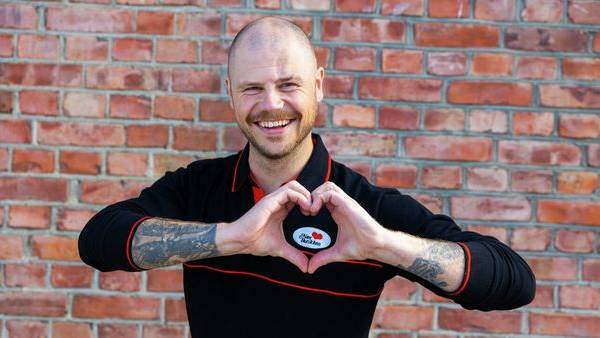 Smilende ansatt i Nærbutikken lager et hjerte med hendene