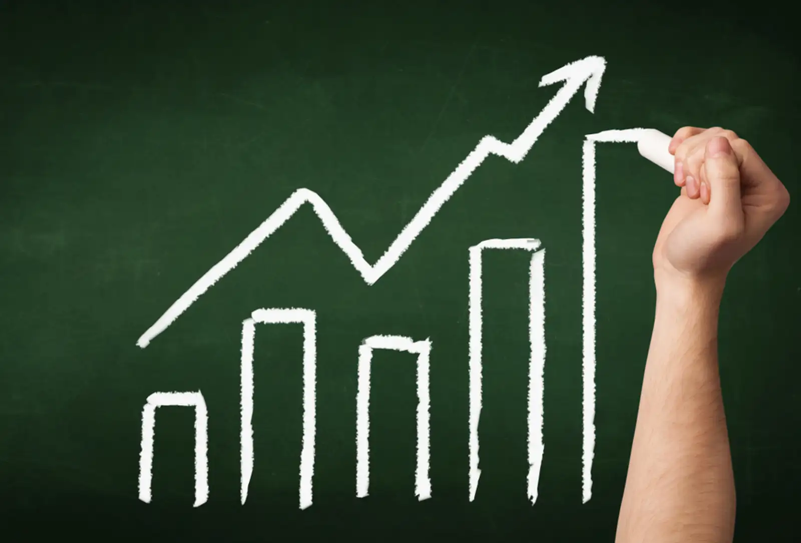 A grown ups hand drawing chart with exponentially growing arrow on green chalkboard.jpeg