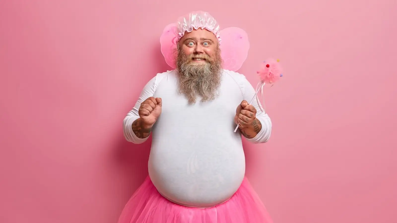 uomo vestito da fata sorride con bacchetta magica in mano e tutu.jpg