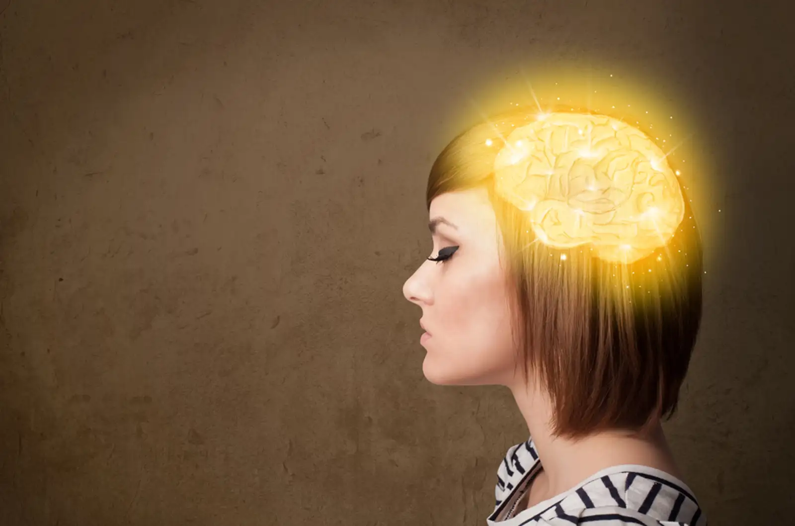 Young girl thinking with glowing brain illustration on grungy background.jpeg