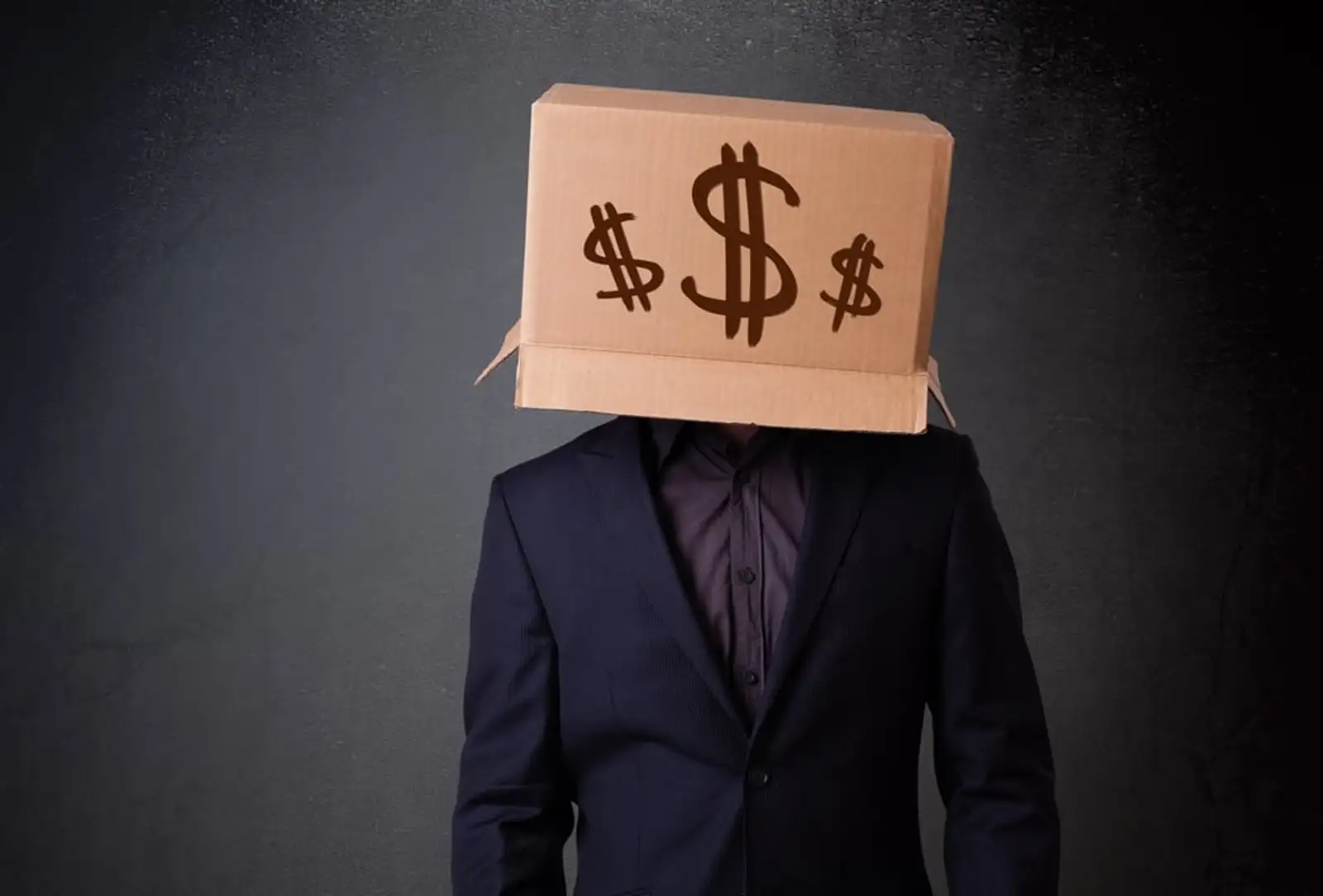 Young man standing and gesturing with a cardboard box on his head with dollar signs.jpeg