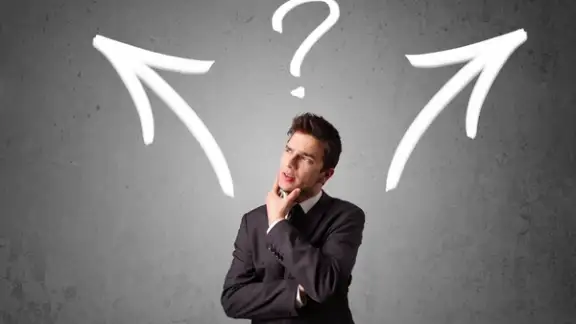 Young businessman taking a decision with arrows and question mark above his head.jpeg