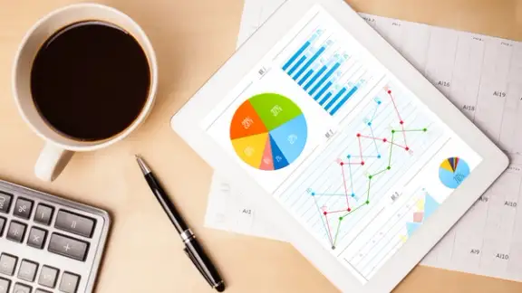 Workplace with tablet pc showing charts and a cup of coffee on a wooden work table close-up-1.jpeg