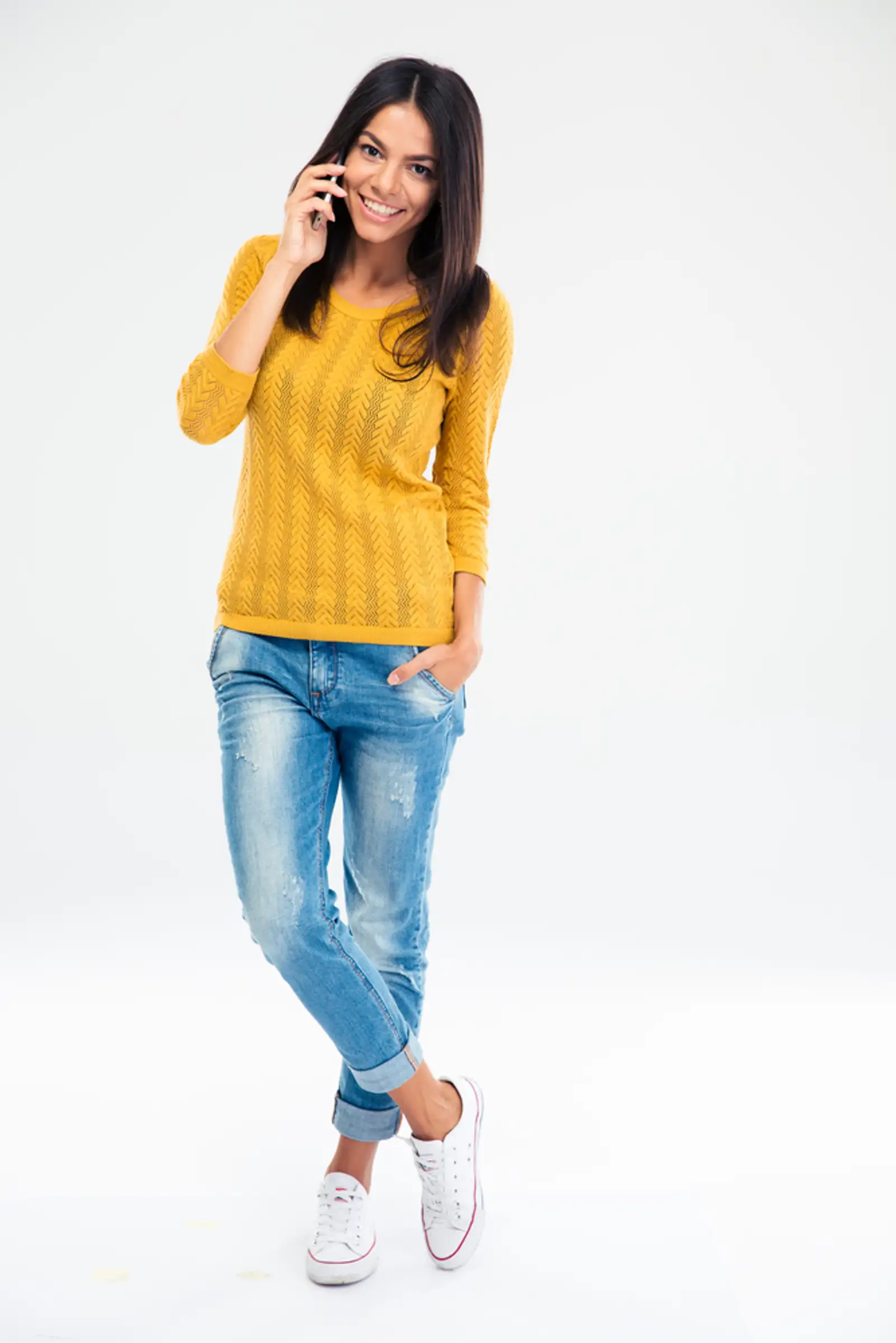 Full length portrait of a happy young woman talking on the phone isolated on a white background.jpeg