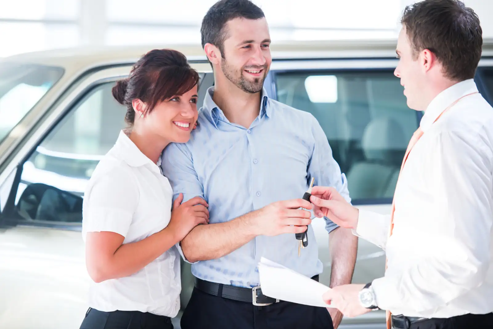 Smiling couple buying a new car from a salesman.jpeg