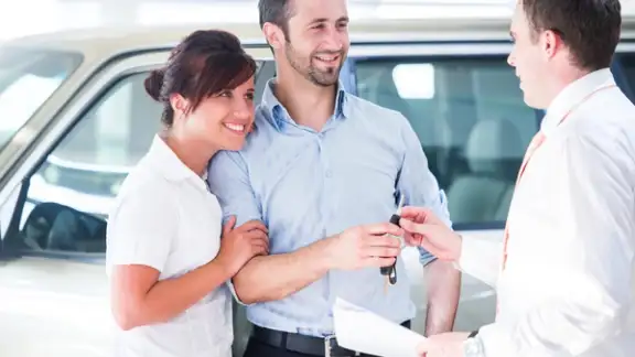 Smiling couple buying a new car from a salesman.jpeg
