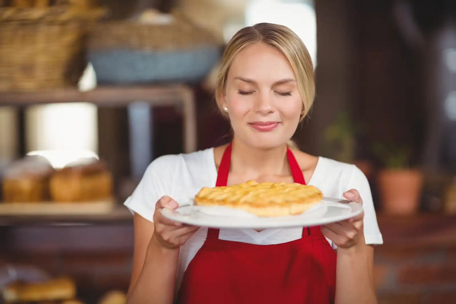 Pretty waitress smelling a plate of cake at the coffee shop.jpeg