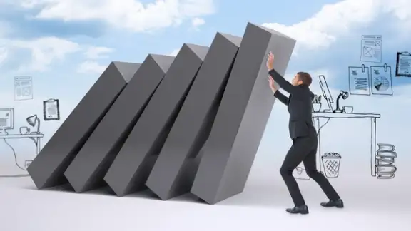 Businessman with his hands up against falling blocks.jpeg