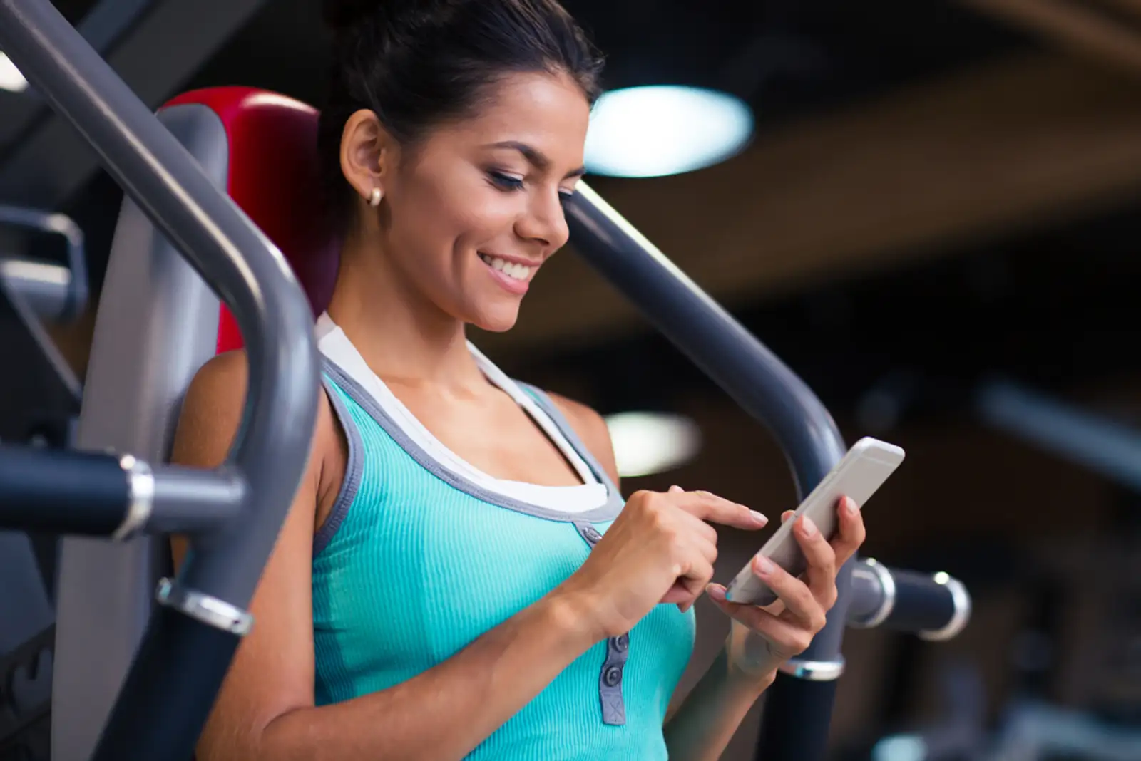 Portrait of a cheerful sports woman using smartphone in fitness gym.jpeg