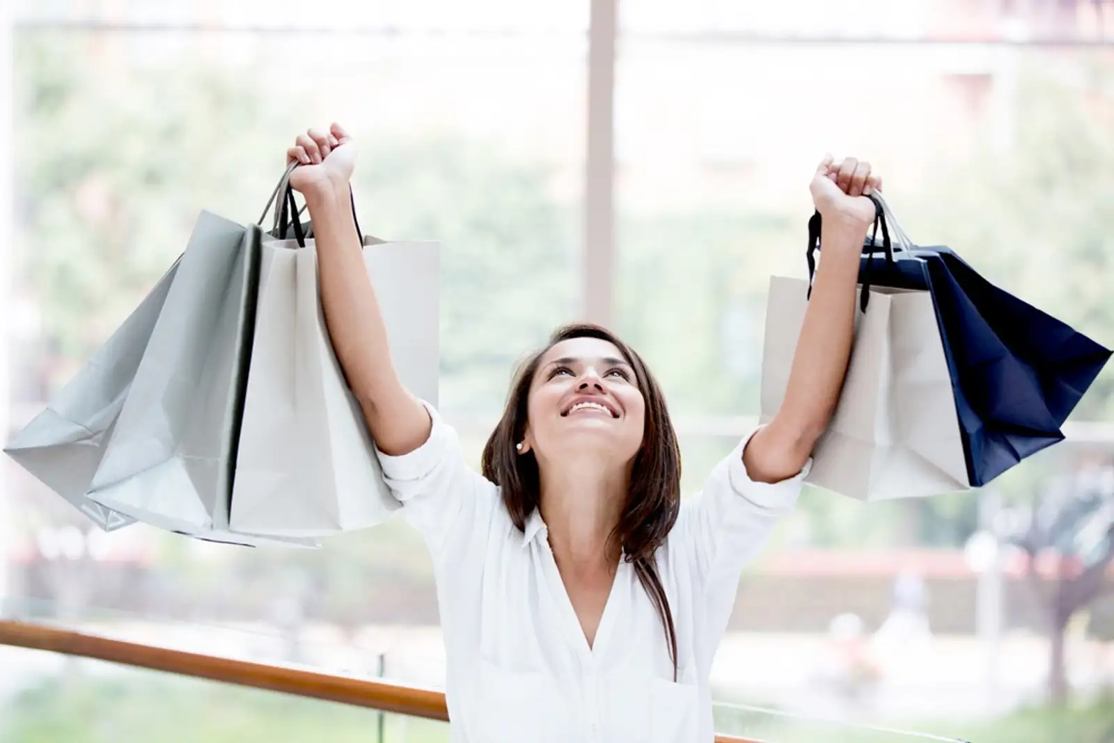 Happy shopping woman with arms up holding bags.jpeg