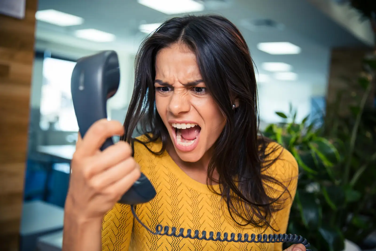 Angry businesswoman shouting on phone in office.jpeg