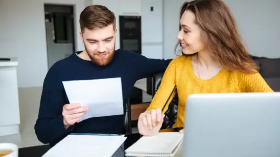 Happy young couple calculating bills at home.jpeg