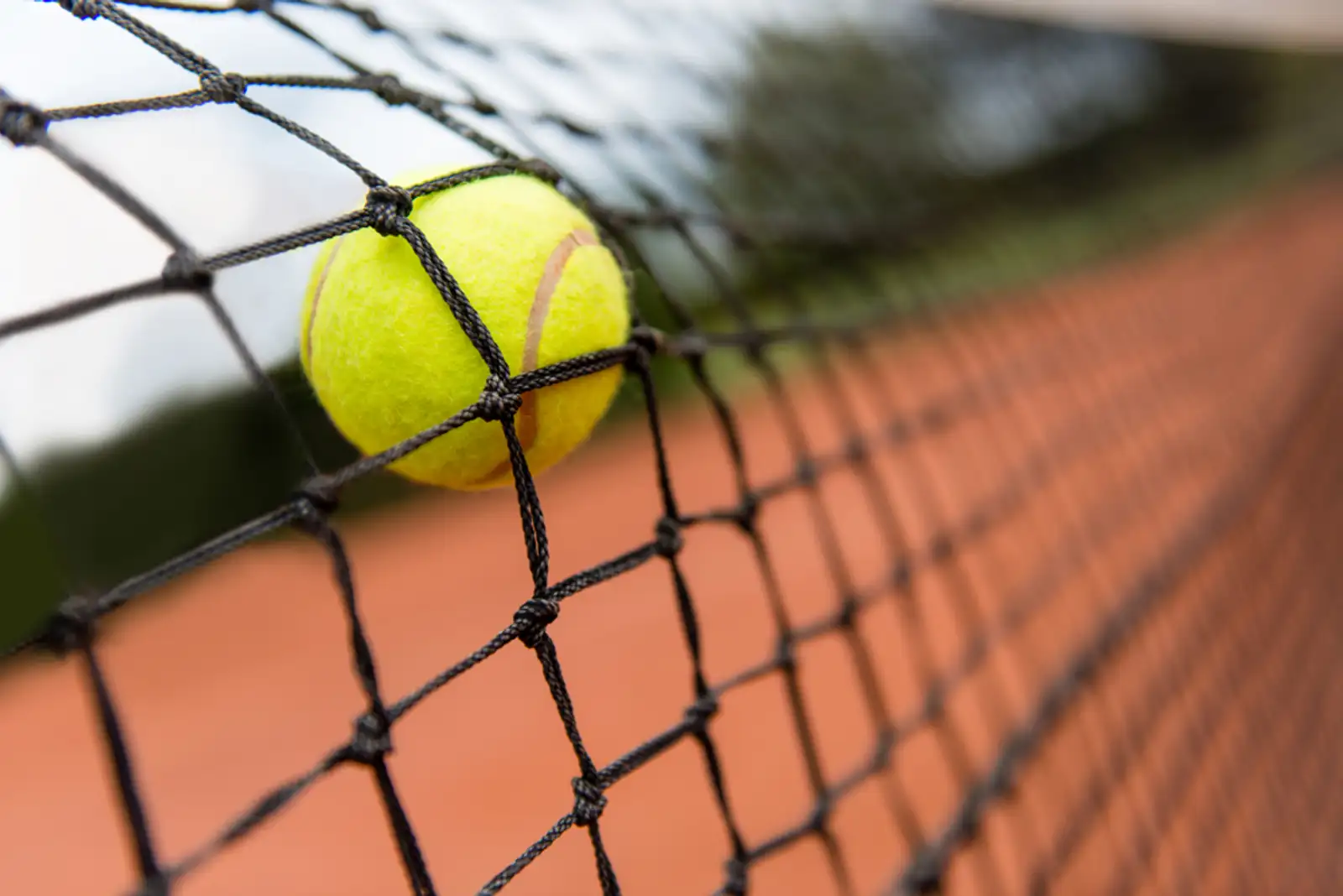 Tennis ball bouncing on the net at a clay court.jpeg