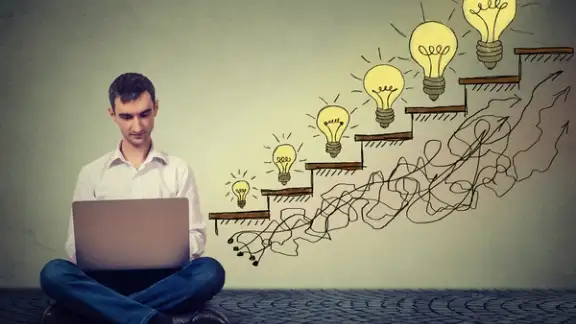 Happy young man entrepreneur working on computer sitting on a floor in his office successful in increasing internet website traffic. Promotion%2c company growth concept. Isolated on gray wall background-1.jpeg