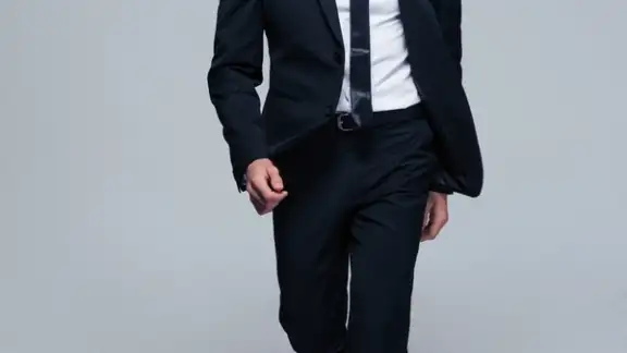Full length portrait of a fashion male model over gray background. Looking at camera.jpeg