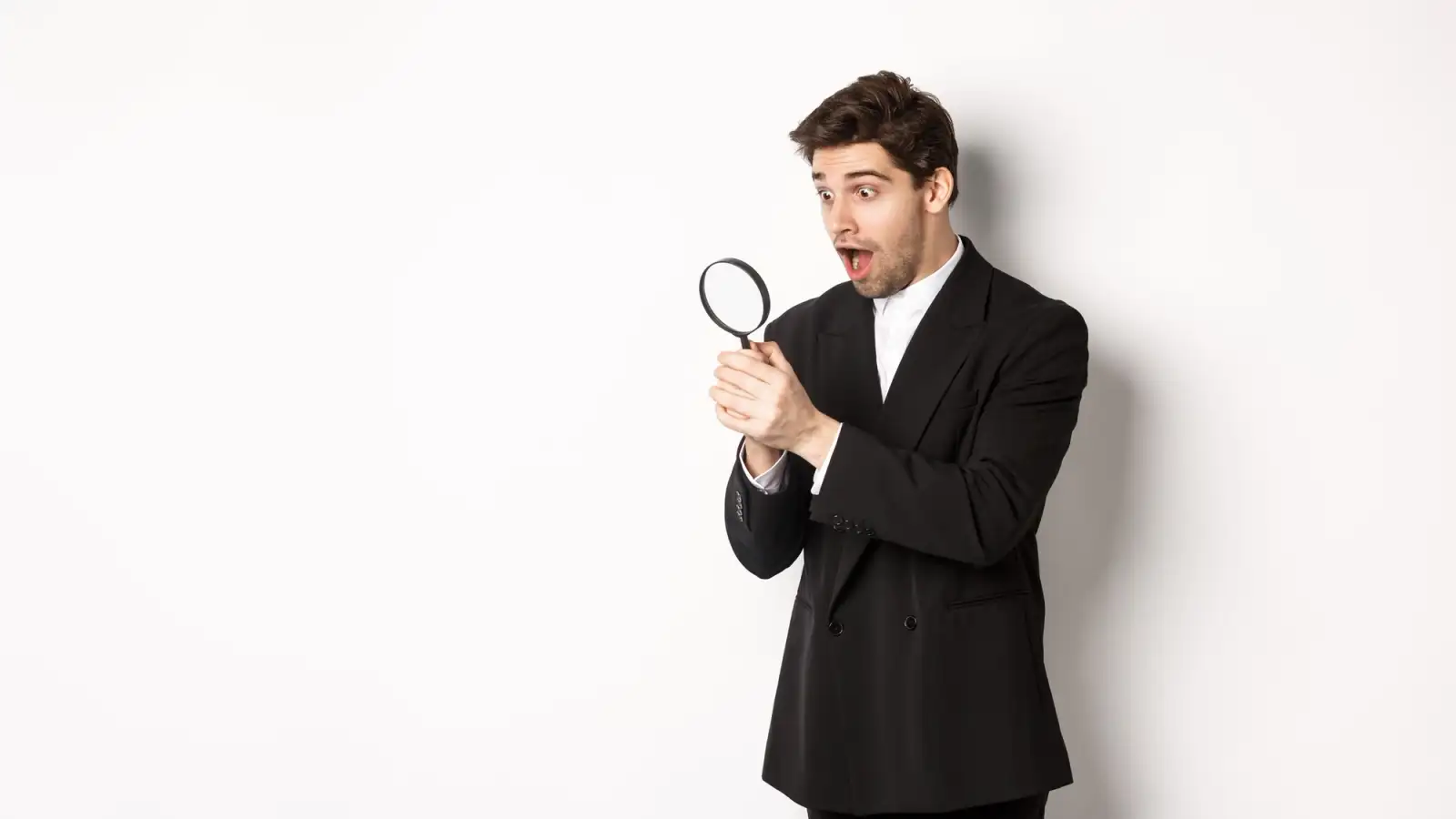 businessman vestito di nero con lente ingrandimento in mano.jpg