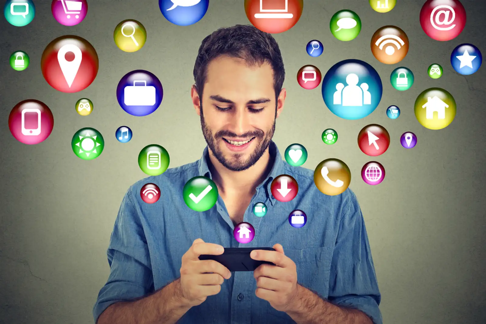 communication technology mobile phone high tech concept. Happy man using texting on smartphone social media application icons flying out of cellphone isolated grey wall background. 4g data plan-1.jpeg