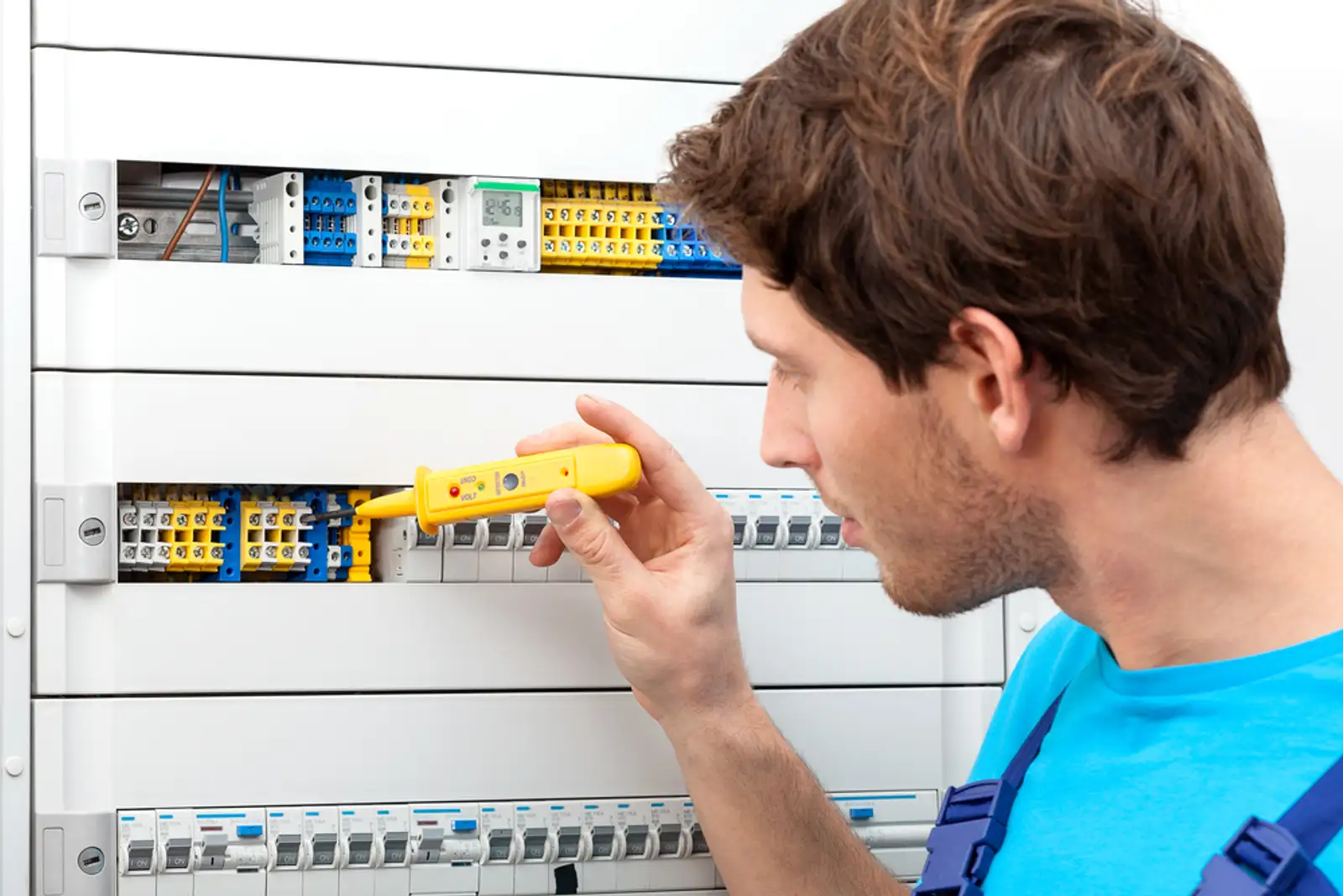 Repairman checking a voltage and fixing a switchboard.jpeg