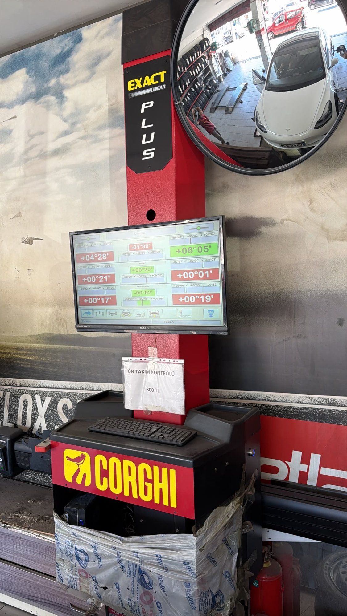 Corghi alignment screen after adjustment, Tesla visible in safety mirror
