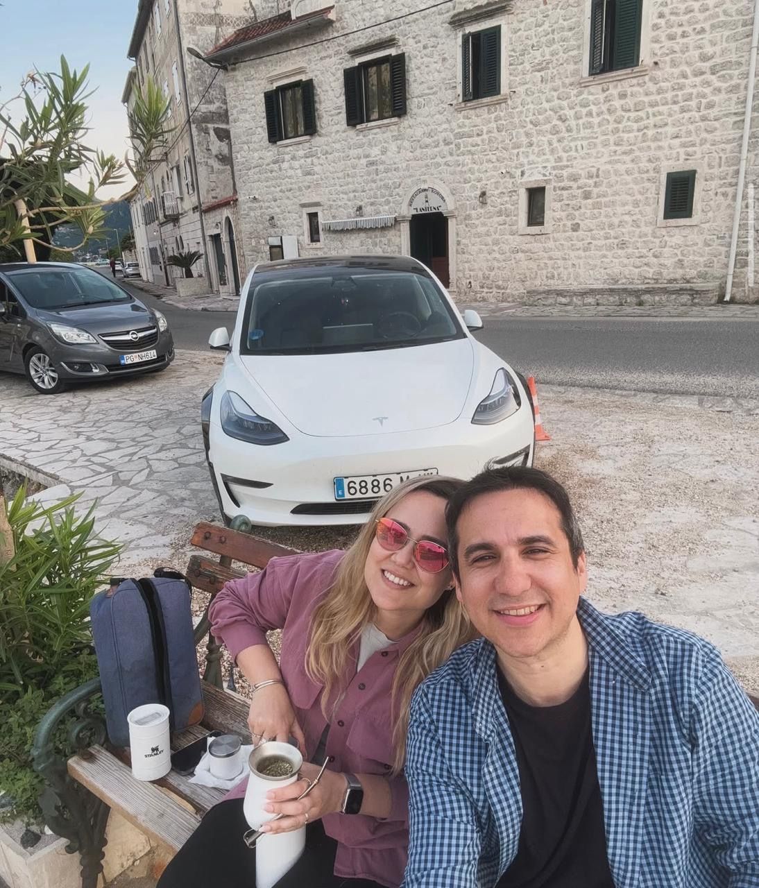Couple with the Tesla and some mate on a stone street in Perast