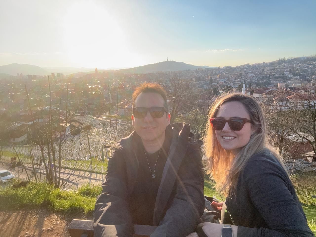 Carla and Gonzalo looking out over the city of Sarajevo from a lookout point, with the cemetery below