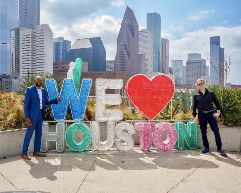 Manuel Bohé mit einem Kollegen vor der We-love-Houston-Skulptur und der Skyline von Houston